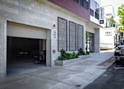 Thumbnail 31 of 36 - Parking garage entrance with motorcycle and landscaping at 68 Beale Apartments, Massachusetts, 02169
